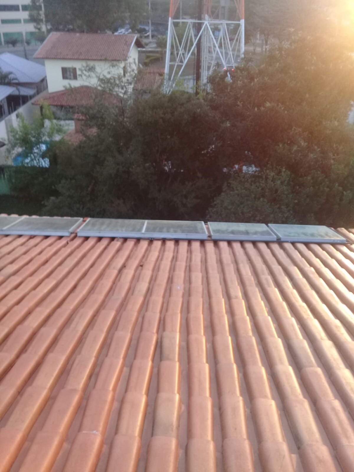 Telhado residencial de telhas cerâmicas recém-limpas com claraboias, mostrando o resultado impecável da lavagem profissional.