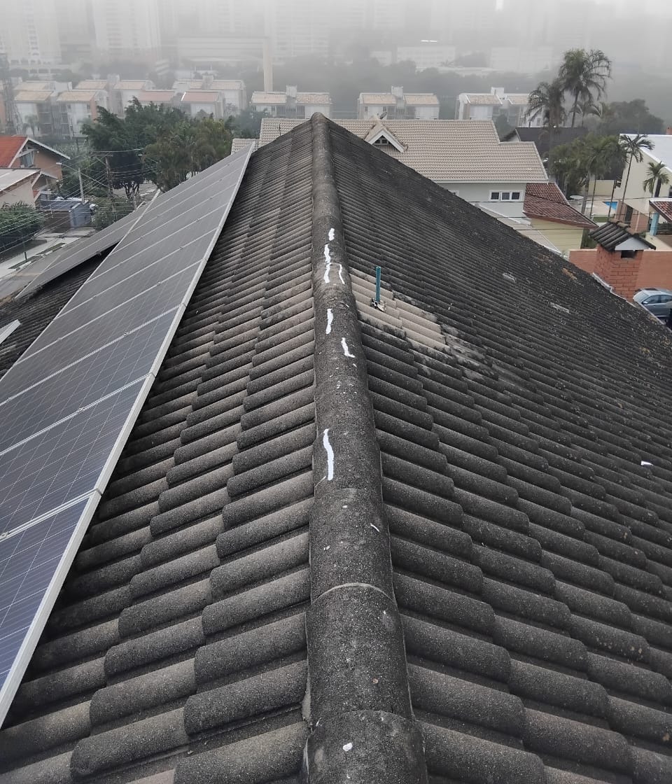 Telhado residencial com telhas escuras acumulado de sujeira e painéis solares, vista do alto em bairro urbano de São José dos Campos