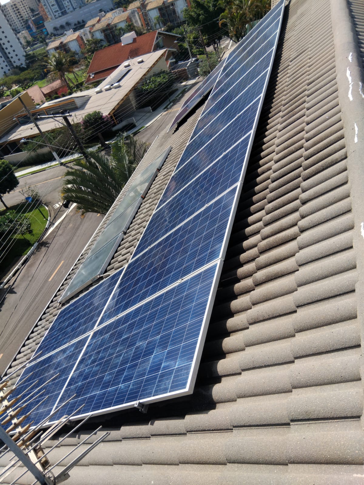 Telhado residencial com painéis solares e telhas limpas, vista de cima em bairro típico de São José dos Campos.