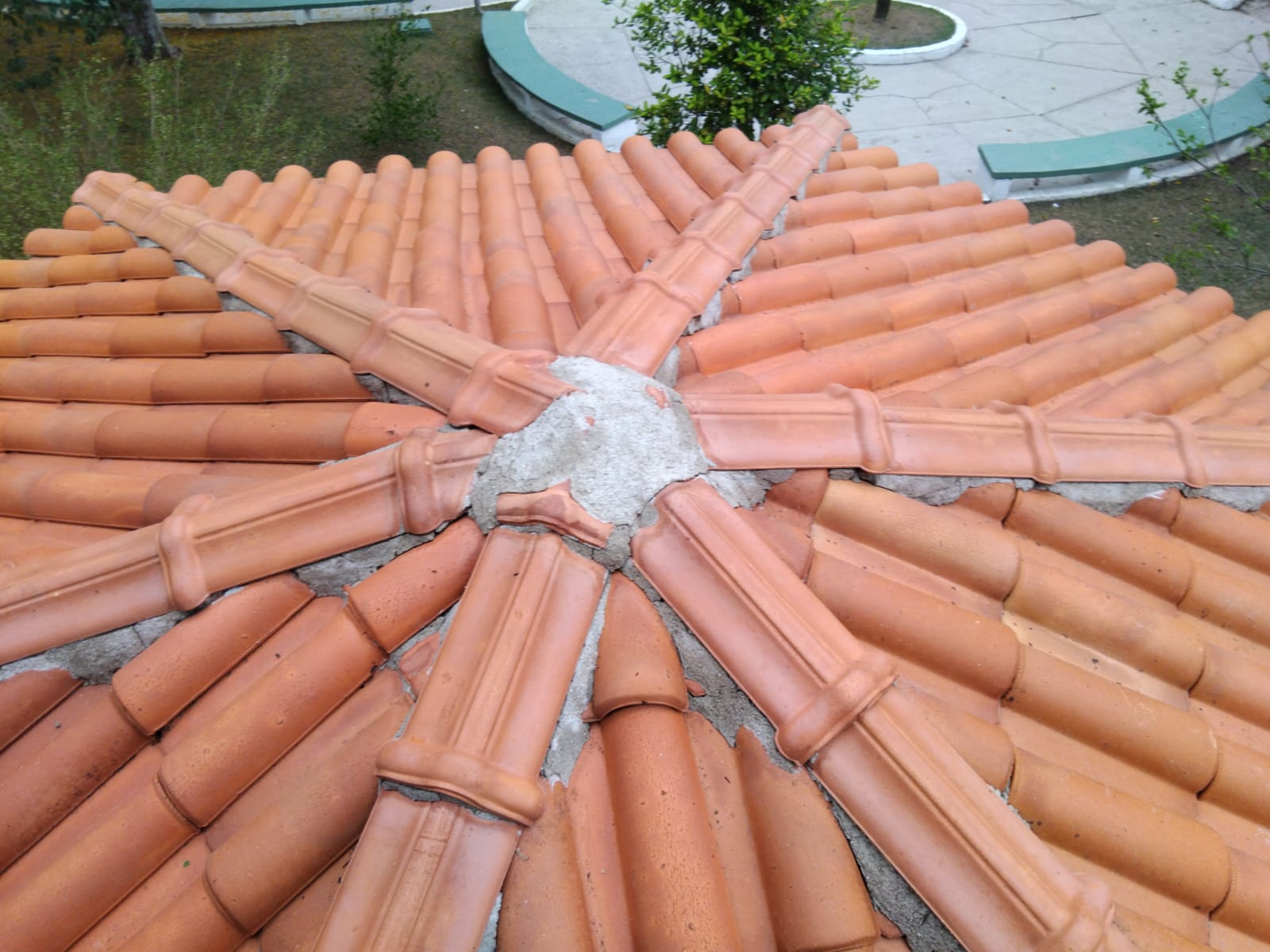 Telhado residencial com telhas de cerâmica em padrão radial ao redor de chaminé, evidenciando o resultado da lavagem profissional realizada.